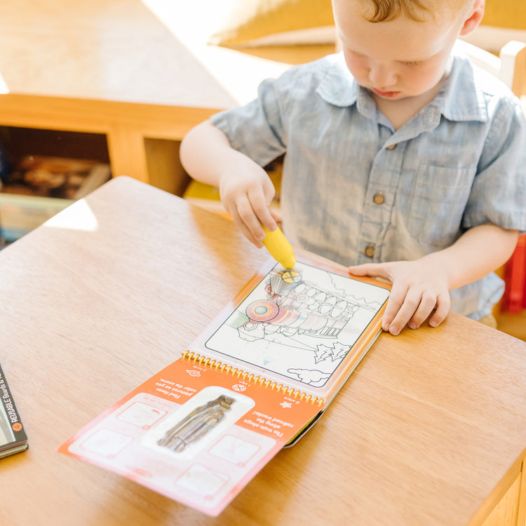 A kid playing with The Melissa & Doug On the Go Water Wow! Reusable Water-Reveal Activity Pad - Vehicles