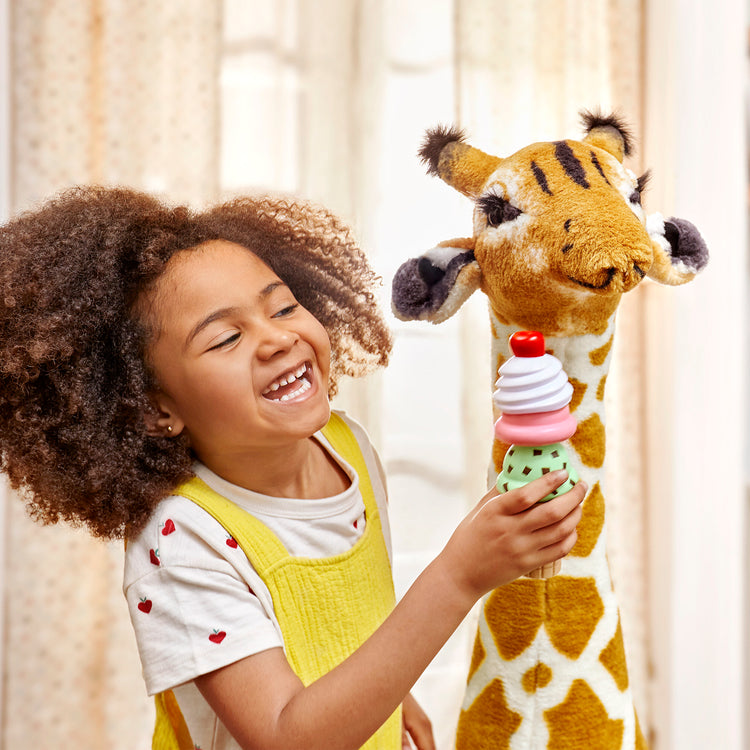 A kid playing with The Melissa & Doug Giant Giraffe - Lifelike Plush Stuffed Animal (over 4 feet tall)