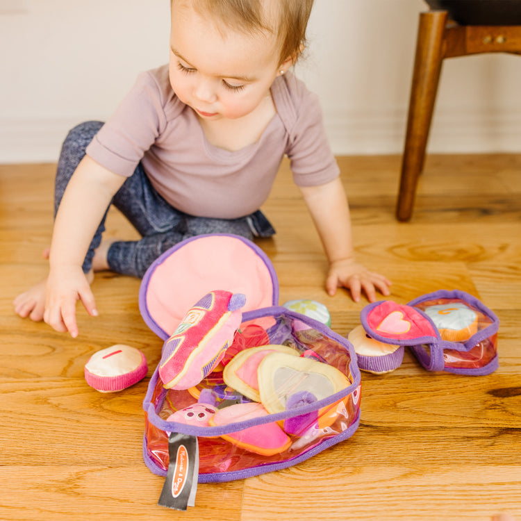 A kid playing with The Melissa & Doug Pretty Purse Fill and Spill Soft Play Set Toddler Toy