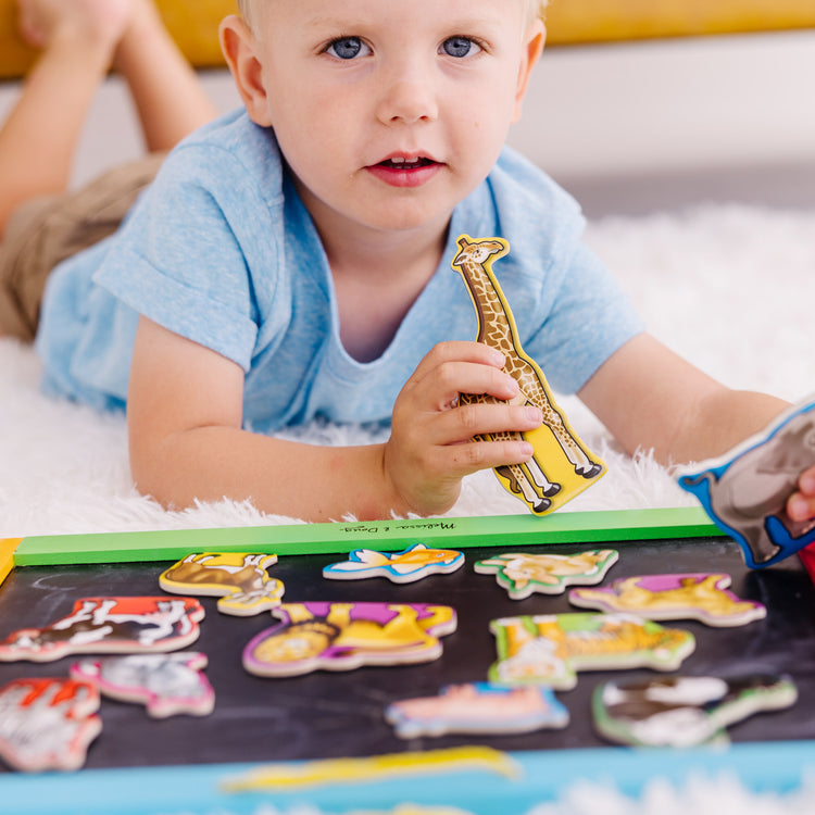 A kid playing with The Melissa & Doug 20 Wooden Animal Magnets in a Box