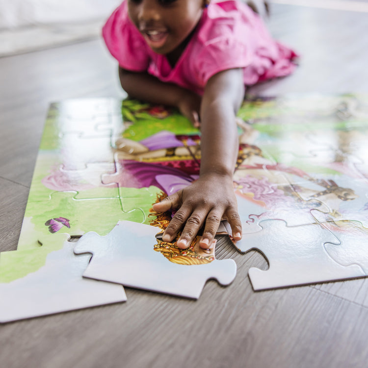 A kid playing with The Melissa & Doug Fairy Tale Castle Jumbo Jigsaw Floor Puzzle (48 pcs, 2 x 3 feet)