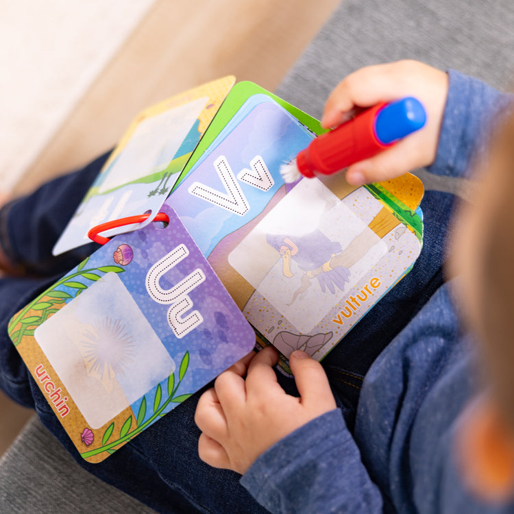 A kid playing with The Melissa & Doug On the Go Water Wow! Reusable Water-Reveal Activity Cards - Alphabet and Animals