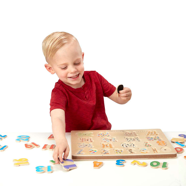 A child on white background with The Melissa & Doug Numbers Sound Puzzle - Wooden Counting Puzzle With Sound Effects (21 pcs)