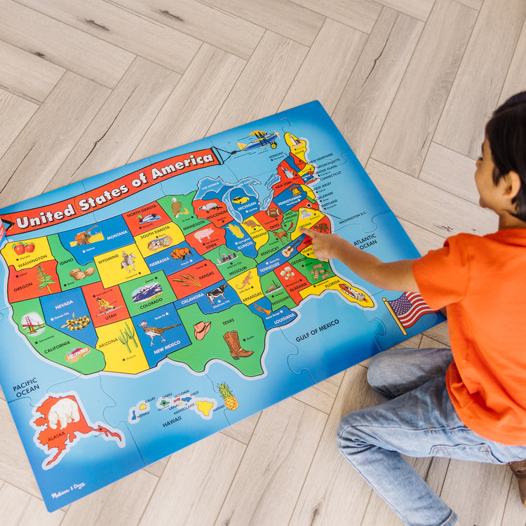 A kid playing with The Melissa & Doug USA Map Floor Puzzle - 51 Pieces (2 x 3 feet)