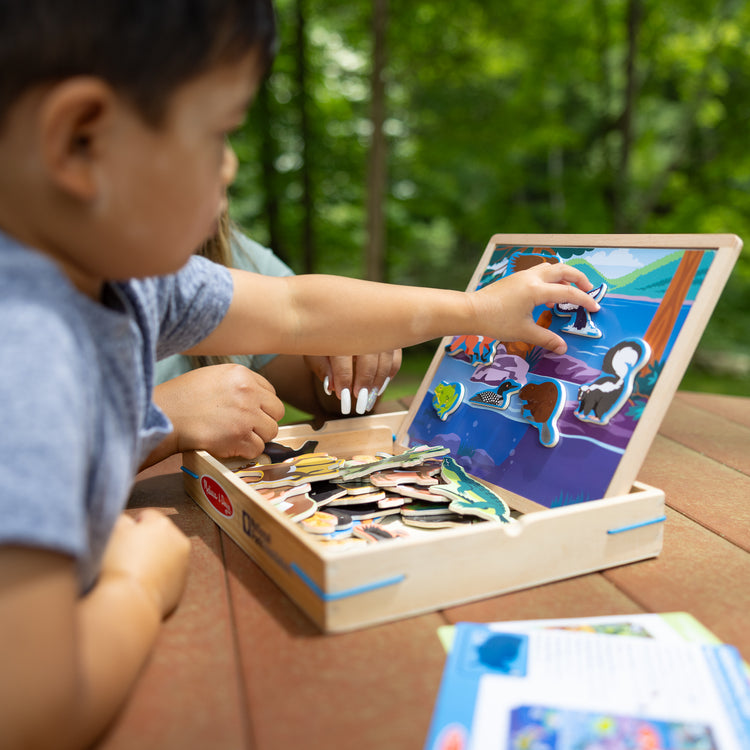 A kid playing with The Melissa & Doug National Parks Wooden Picture Matching Magnetic Game