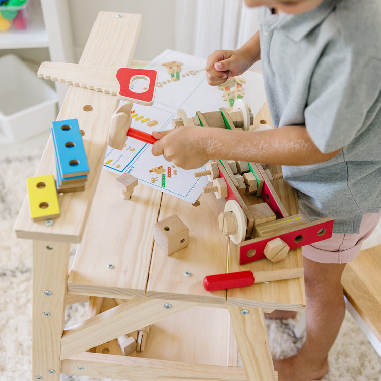 A kid playing with The Melissa & Doug Solid Wood Project Workbench Play Building Set