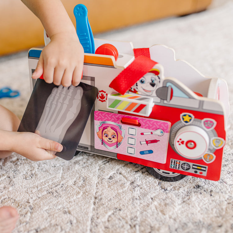 A kid playing with The Melissa & Doug PAW Patrol Marshall's Wooden Rescue EMT Caddy (14 Pieces)