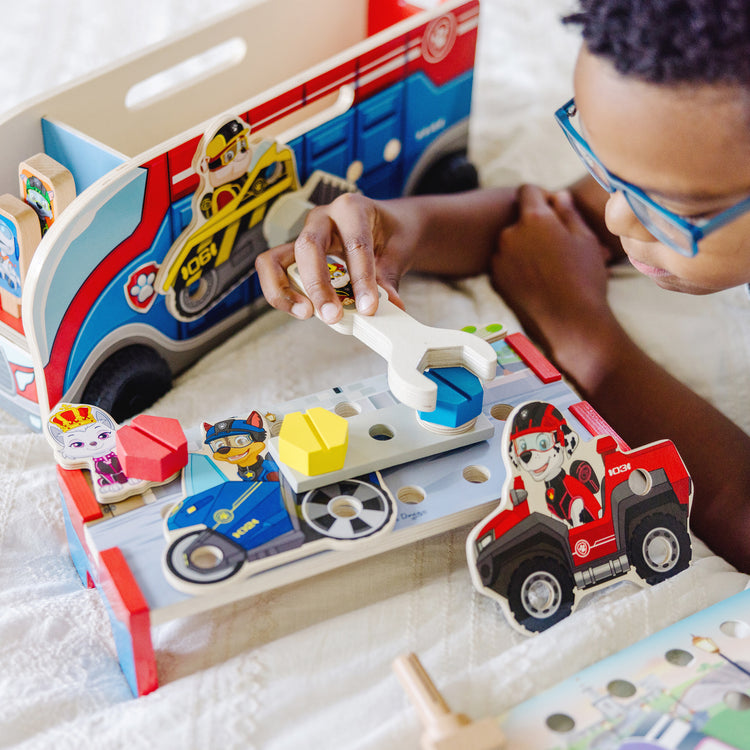 A kid playing with The Melissa & Doug PAW Patrol Match & Build Mission Cruiser