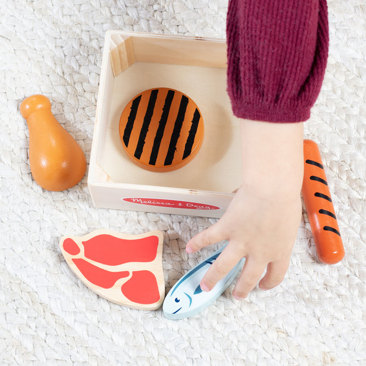 A kid playing with The Melissa & Doug Wooden Food Groups Play Food Set – Protein