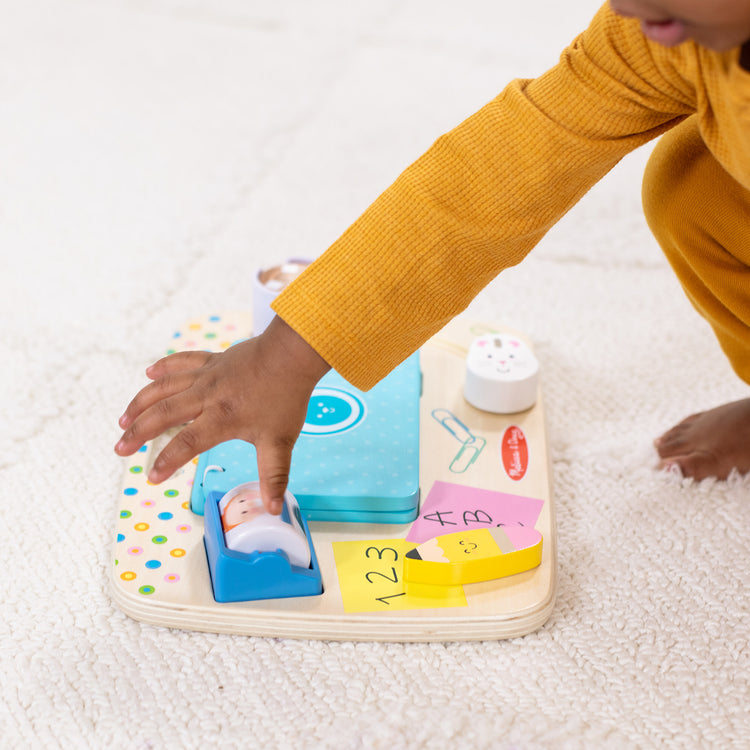 A kid playing with The Melissa & Doug Wooden Work & Play Desktop Activity Board Infant and Toddler Sensory Toy