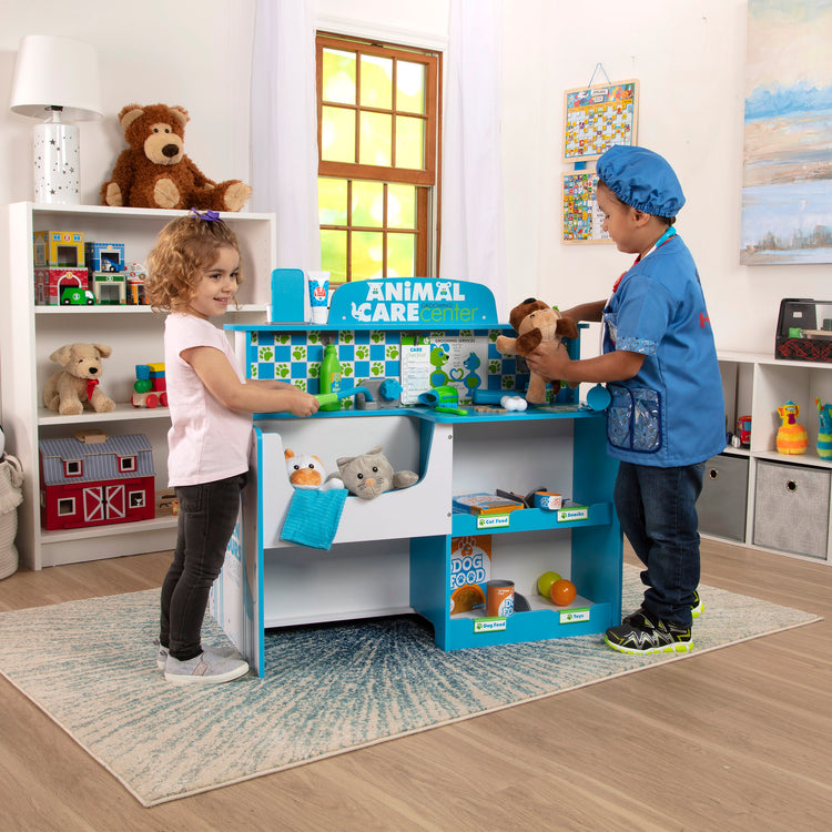 A kid playing with The Melissa & Doug Animal Care Veterinarian and Groomer Wooden Activity Center for Plush Stuffed Pets (Not Included)