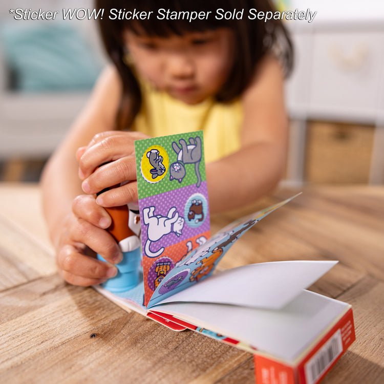 A kid playing with The Melissa & Doug Sticker WOW!™ Mini Activity Pad and 200+ Refill Stickers for Sticker Stamper Arts and Crafts Fidget Toy Collectibles – Pets Stickers