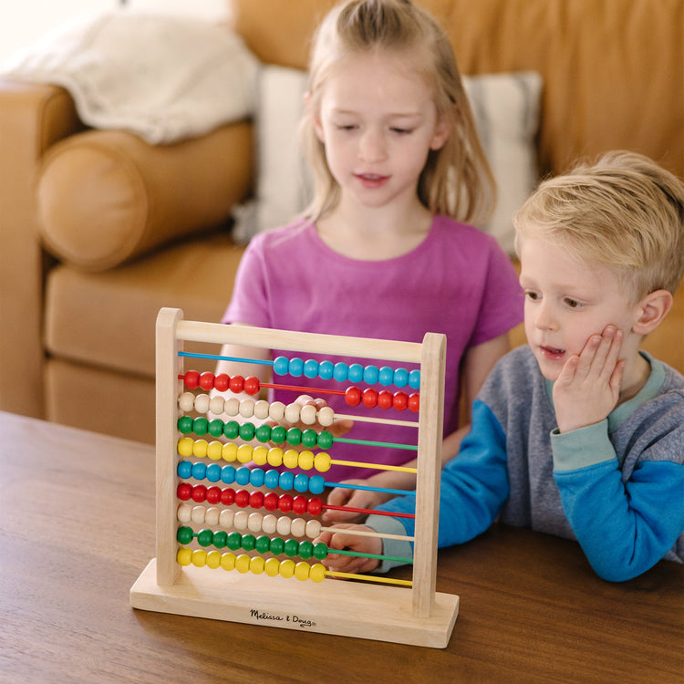 A kid playing with The Melissa & Doug Abacus - Classic Wooden Educational Counting Toy With 100 Beads