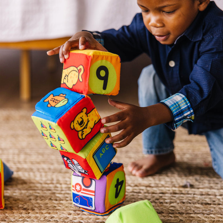 A kid playing with The Melissa & Doug K's Kids Match and Build Soft Blocks Set