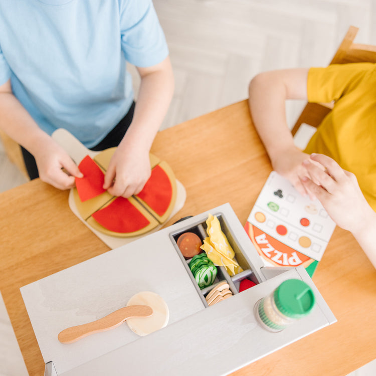 A kid playing with The Melissa & Doug Top & Bake Wooden Pizza Counter Play Set (41 Pcs)