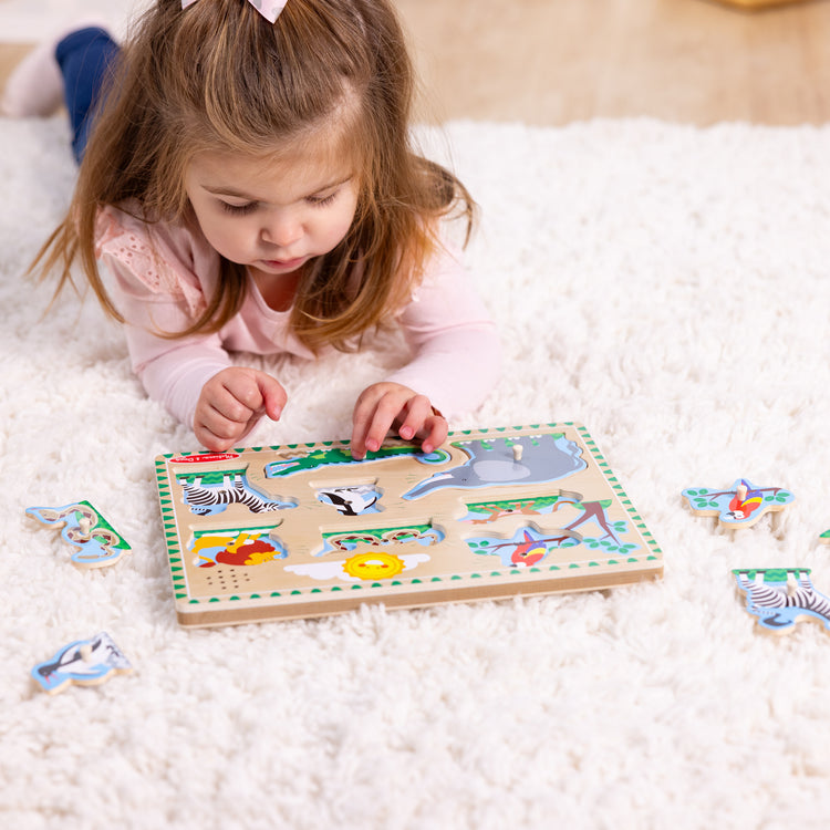 A kid playing with The Melissa & Doug Zoo Animals Sound Puzzle - Wooden Peg Puzzle With Sound Effects (8 pcs)