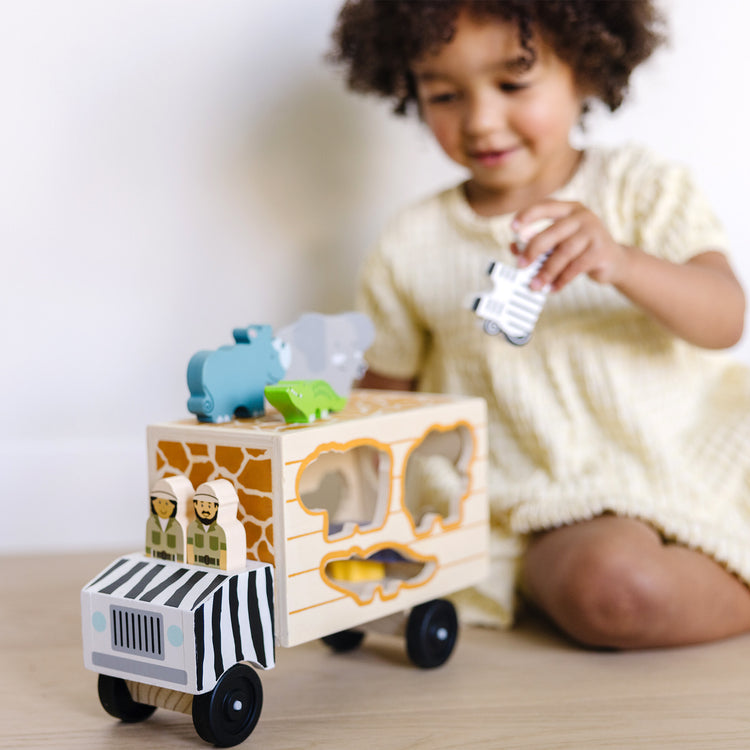 A kid playing with The Melissa & Doug Animal Rescue Shape-Sorting Truck - Wooden Toy With 7 Animals and 2 Play Figures