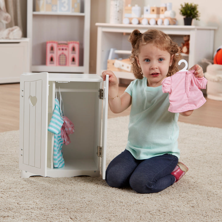 A kid playing with The Melissa & Doug Mine to Love Wooden Play Armoire Closet for Dolls, Stuffed Animals - White (17.3”H x 12.4”W x 8.5”D Assembled)