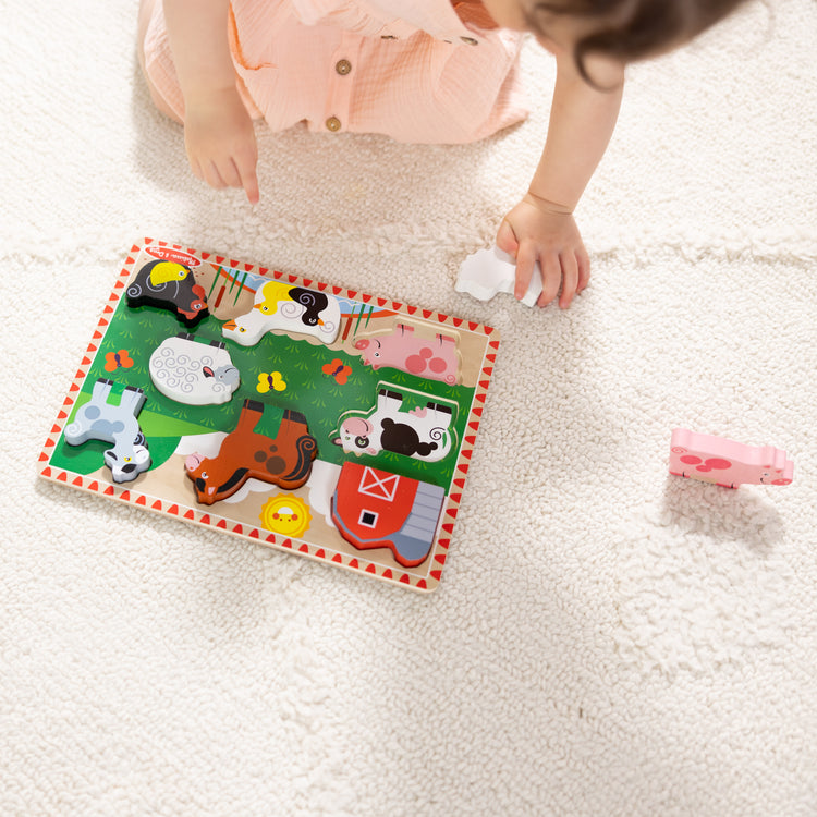 A kid playing with The Melissa & Doug Farm Wooden Chunky Puzzle (8 pcs)