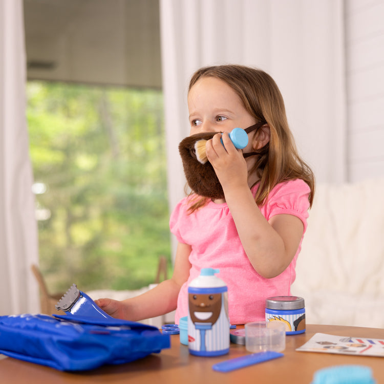 A kid playing with The Melissa & Doug Barber Shop Pretend Play Set Shaving Toy for Boys and Girls Ages 3+