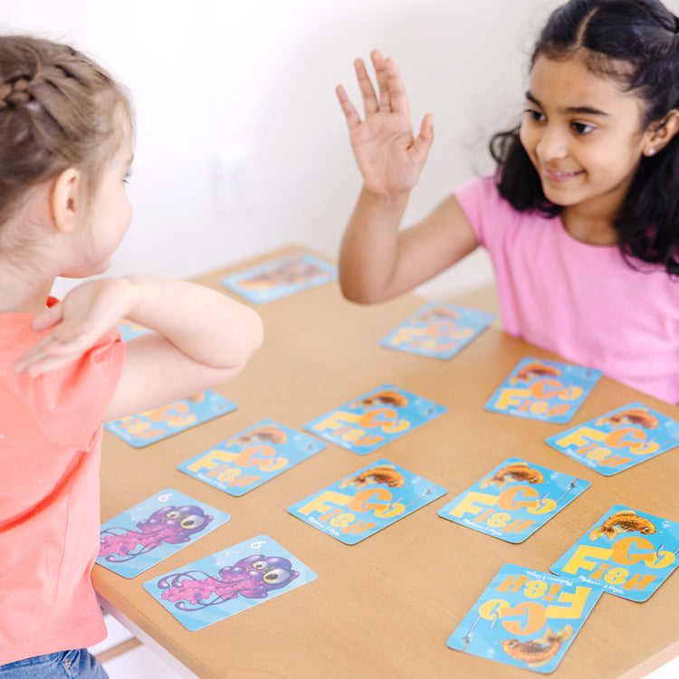 A kid playing with The Melissa & Doug Classic Card Games Set - Old Maid, Go Fish, Rummy