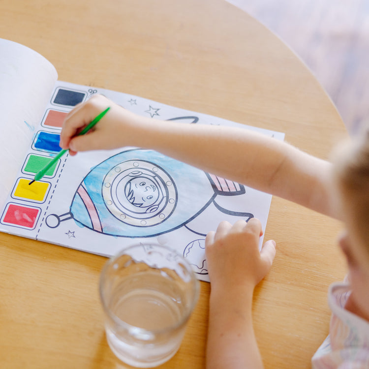 A kid playing with The Melissa & Doug Paint With Water - Vehicles, 20 Perforated Pages With Spillproof Palettes