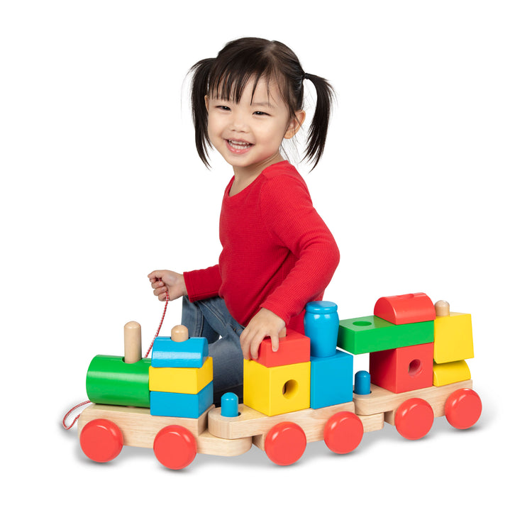 A child on white background with The Melissa & Doug Wooden Jumbo Stacking Train – 4-Color Classic Wooden Toddler Toy (17 pcs)