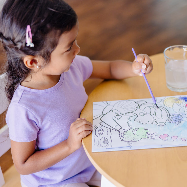 A kid playing with The Melissa & Doug Paint With Water - Princess, 20 Perforated Pages With Spillproof Palettes