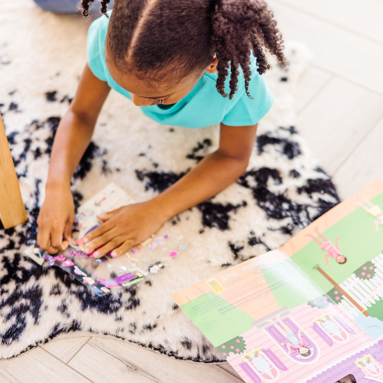 A kid playing with The Melissa & Doug Puffy Sticker Activity Book: Dress-Up - 76 Reusable Stickers