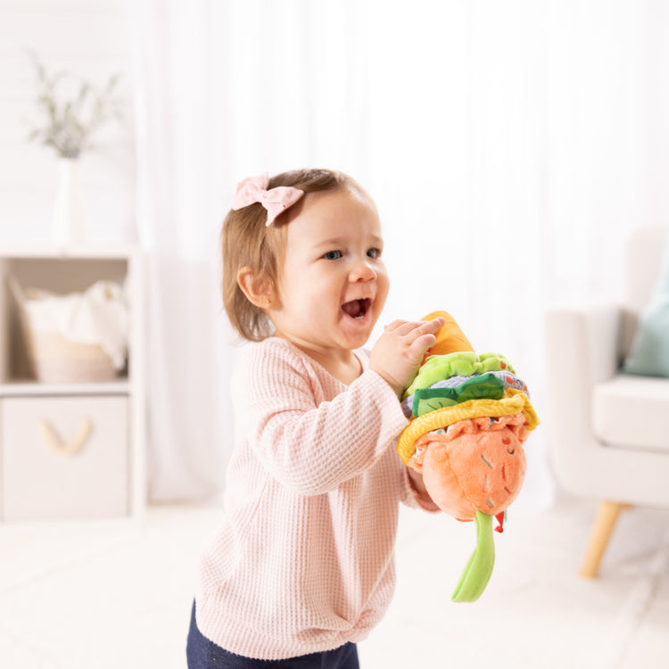 A kid playing with The Melissa & Doug Ice Cream Take-Along Clip-On Infant Toy with Sound and Vibration