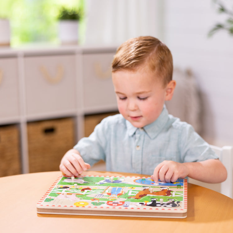 A kid playing with The Melissa & Doug Old MacDonald's Farm Sound Puzzle