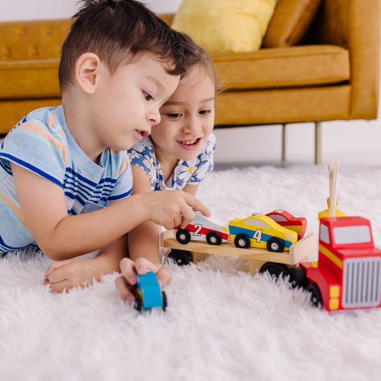 A kid playing with The Melissa & Doug Magnetic Car Loader Wooden Toy Set With 4 Cars and 1 Semi-Trailer Truck