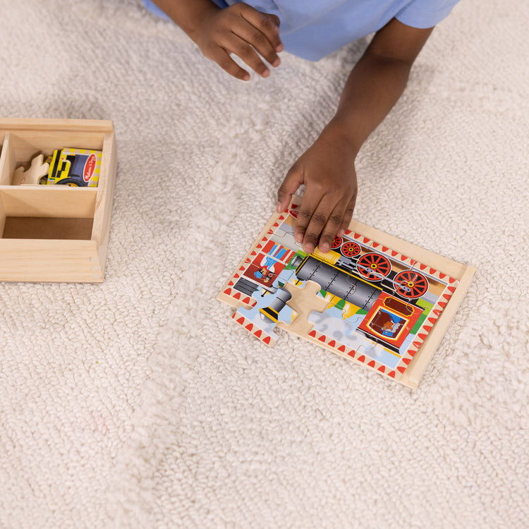 A kid playing with The Melissa & Doug Vehicles 4-in-1 Wooden Jigsaw Puzzles in a Storage Box (48 pcs)