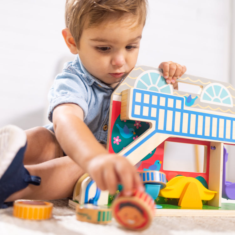 A kid playing with The Melissa & Doug GO Tots Wooden Schoolyard Tumble with 4 Disks