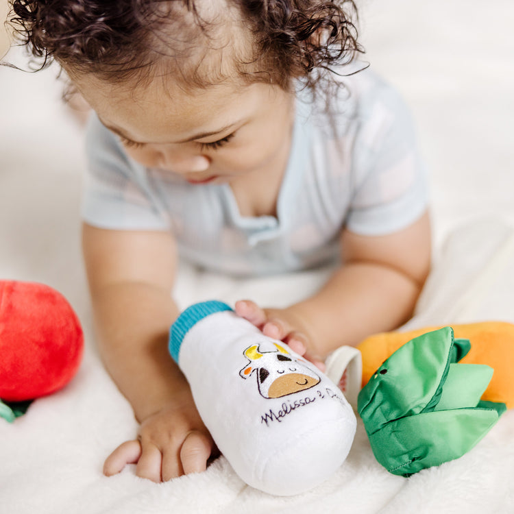 A kid playing with The Melissa & Doug Multi-Sensory Market Basket Fill & Spill Infant Toy