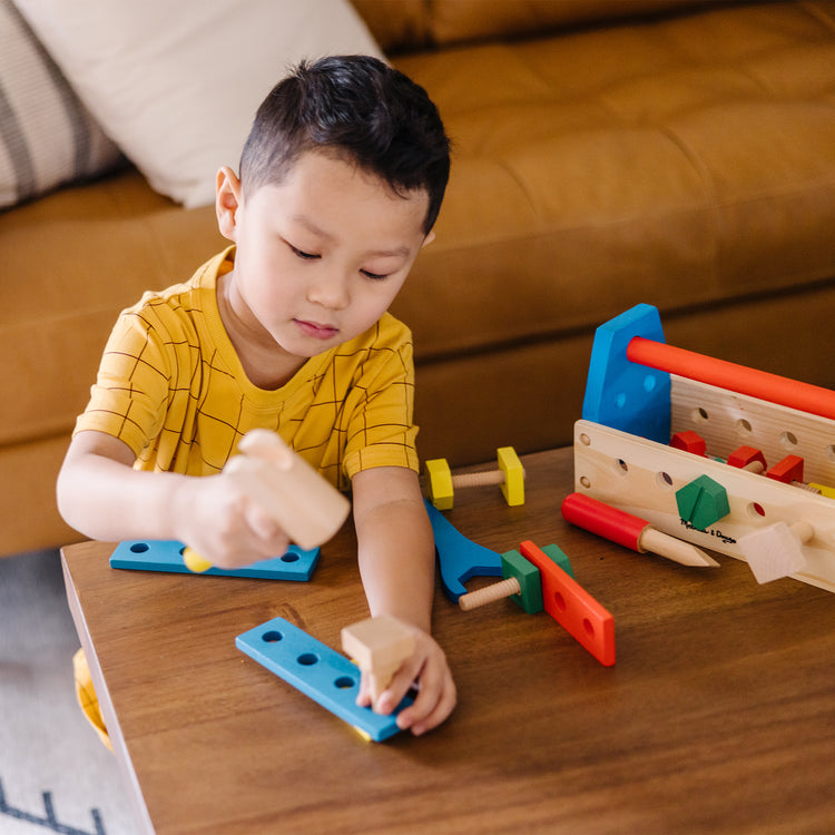 A kid playing with The Melissa & Doug Take-Along Tool Kit Wooden Construction Toy (24 pcs)