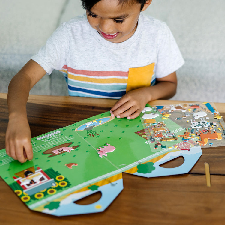 A kid playing with The Melissa & Doug Puffy Sticker Play Set - On the Farm - 52 Reusable Stickers, 2 Fold-Out Scenes