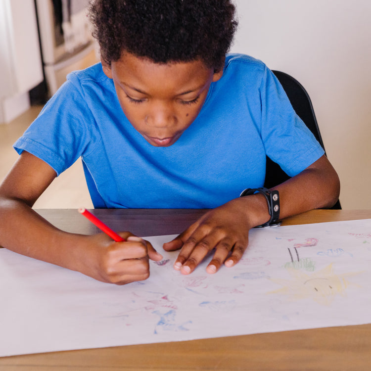 A kid playing with The Melissa & Doug Wooden Stamp Set: Dinosaurs - 8 Stamps, 5 Colored Pencils, 2-Color Stamp Pad