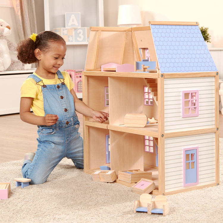 A kid playing with The Melissa & Doug Modern Wooden Multi-Level Dollhouse With 19 pcs Furniture [White]