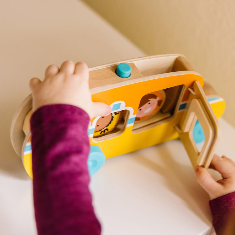 A kid playing with The Melissa & Doug GO Tots Wooden Roll & Ride Bus with 3 Disks