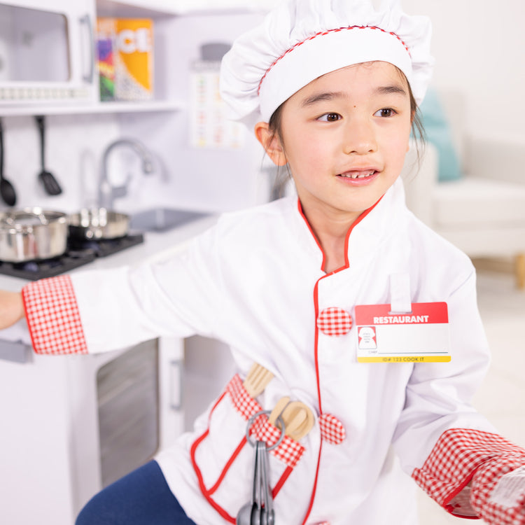 A kid playing with The Melissa & Doug Chef Role Play Costume Dress -Up Set With Realistic Accessories