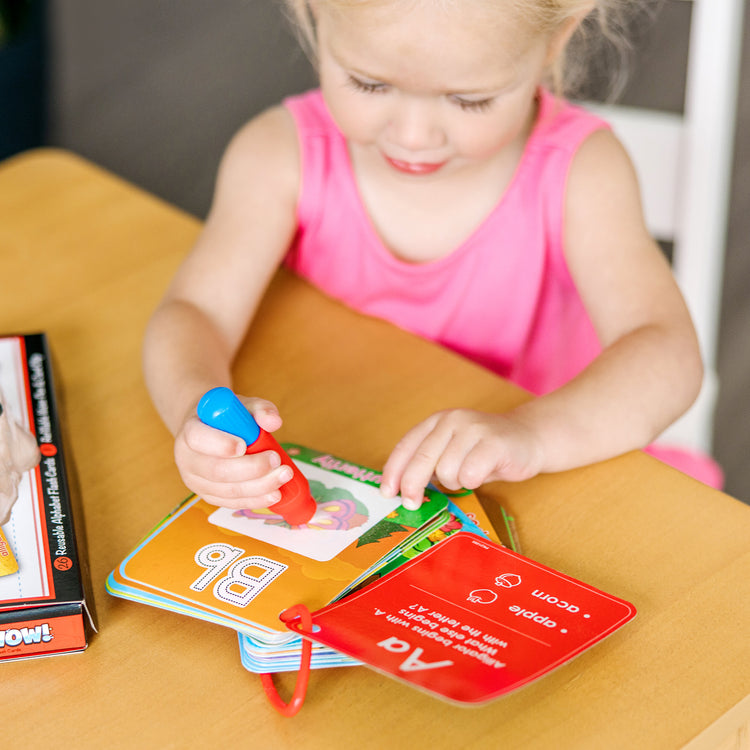 A kid playing with The Melissa & Doug On the Go Water Wow! Reusable Water-Reveal Activity Cards - Alphabet and Animals