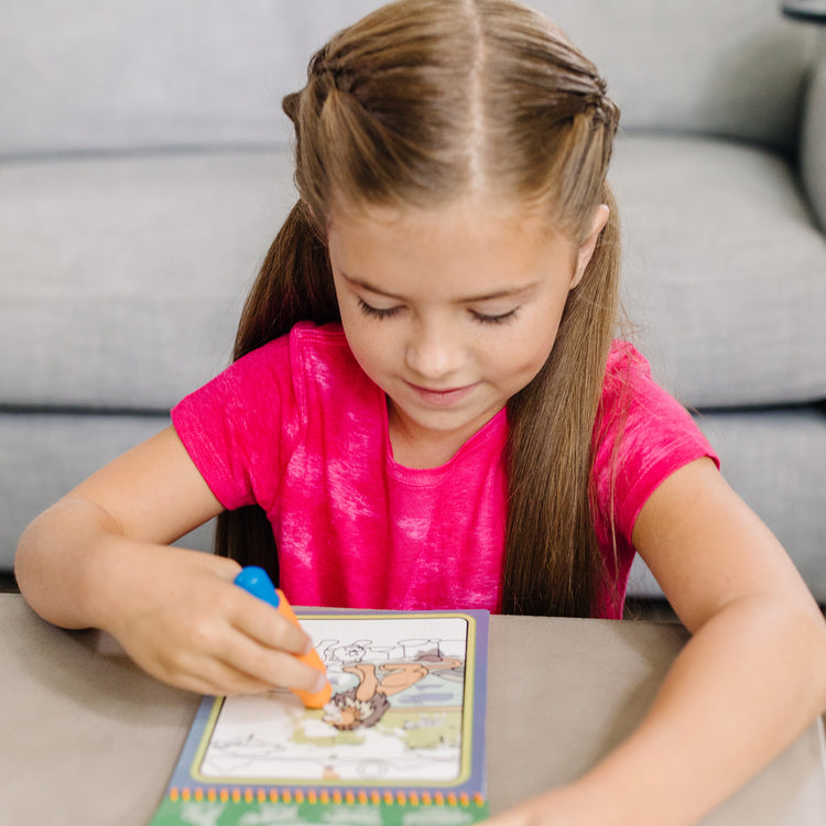 A kid playing with The Melissa & Doug On the Go Water Wow! Reusable Water-Reveal Activity Pad - Safari