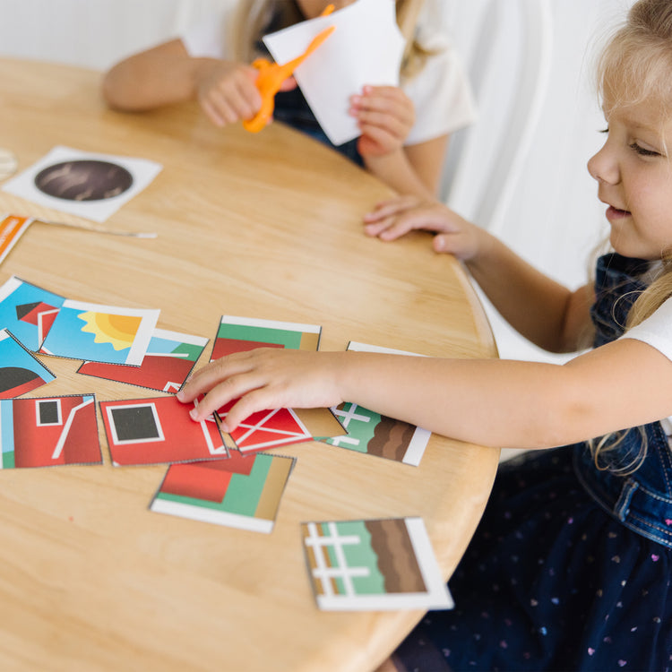 A kid playing with The Melissa & Doug Scissor Skills Activity Book With Pair of Child-Safe Scissors (20 Pages)