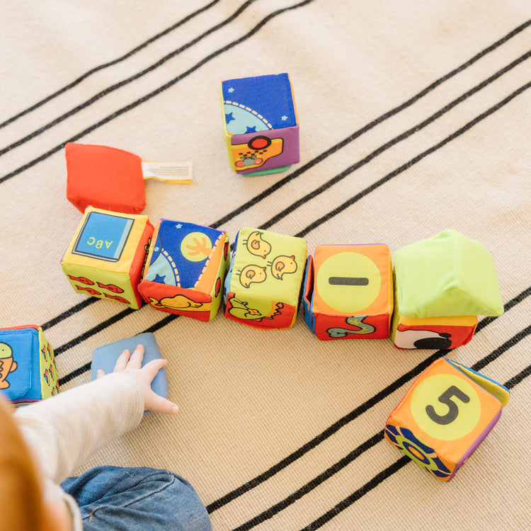 A kid playing with The Melissa & Doug K's Kids Match and Build Soft Blocks Set