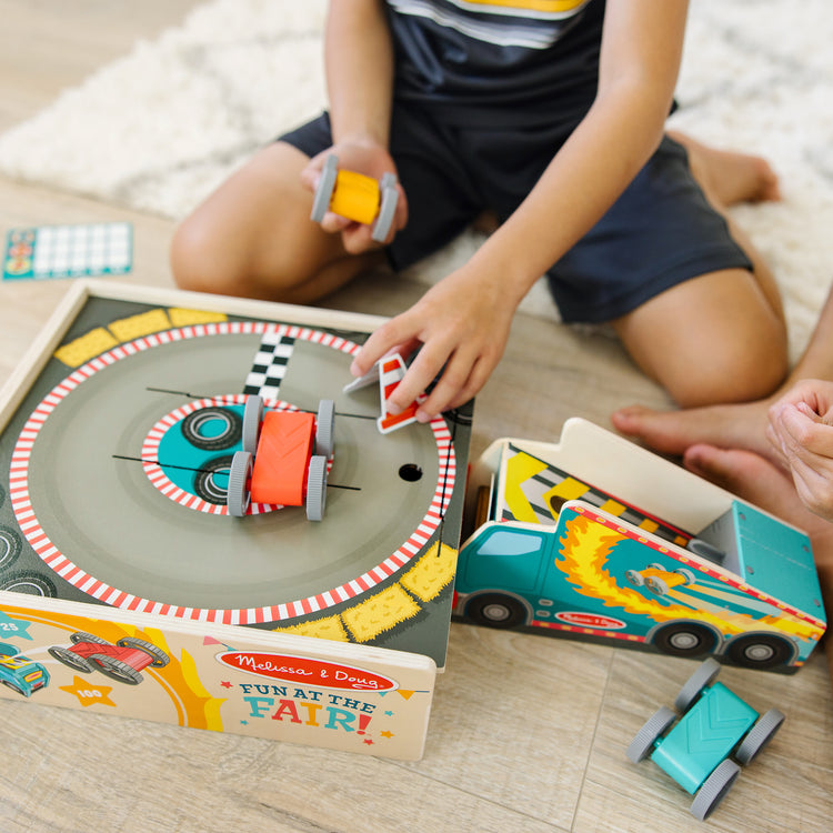 A kid playing with The Melissa & Doug Fun at the Fair! Wooden Ring of Fire Stunt Jumper Cars Game