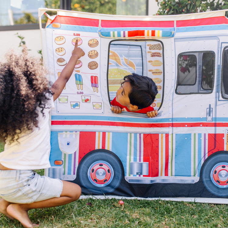 A kid playing with The Melissa & Doug Fabric Double-Sided Food Truck Play Tent - Ice Cream And BBQ