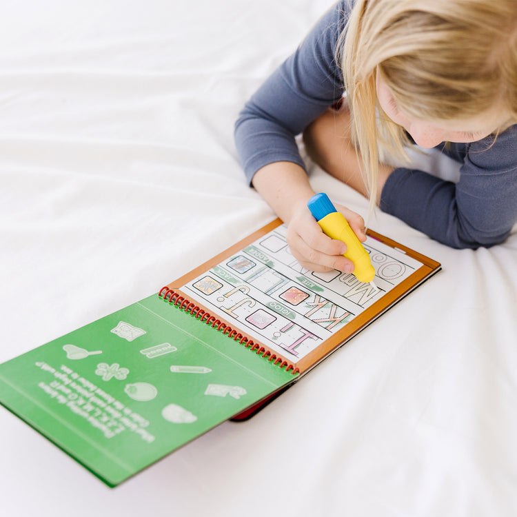 A kid playing with The Melissa & Doug On the Go Water Wow! Reusable Water-Reveal Activity Pad - Alphabet