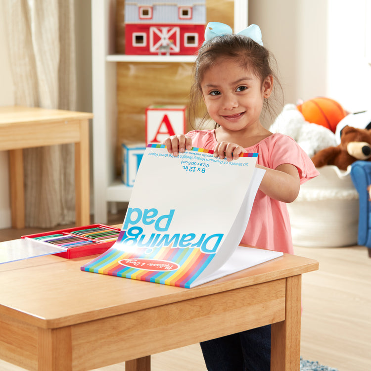 A kid playing with The Melissa & Doug Drawing Pad (9 x 12 inches) With 50 Sheets of White Bond Paper