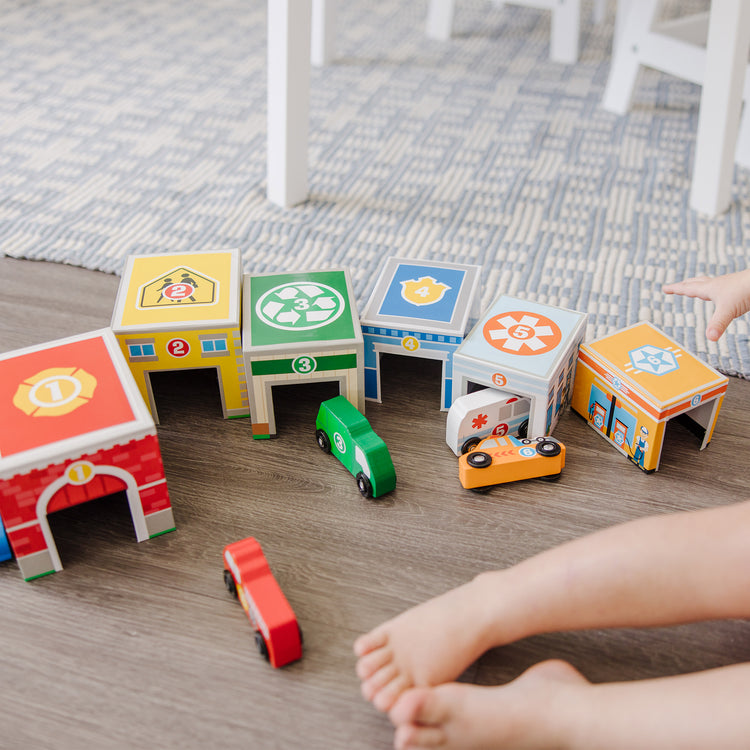 A kid playing with The Melissa & Doug Nesting and Sorting Blocks - 6 Buildings, 6 Wooden Vehicles